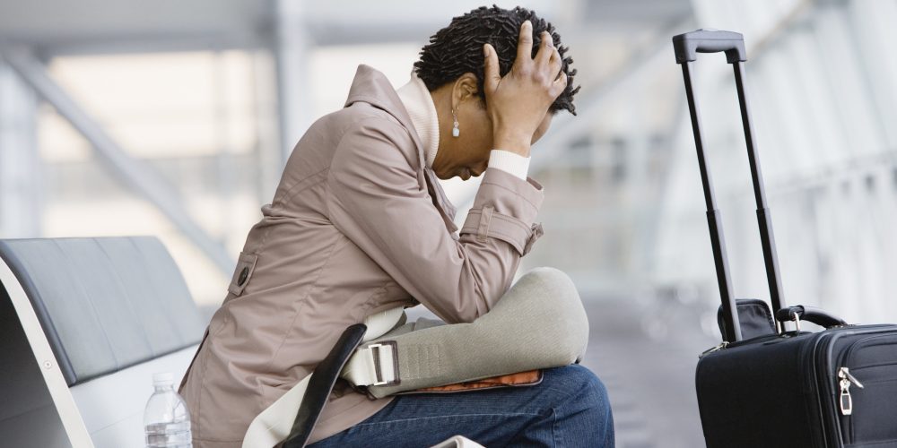 Woman with head in hands sitting on airport bench